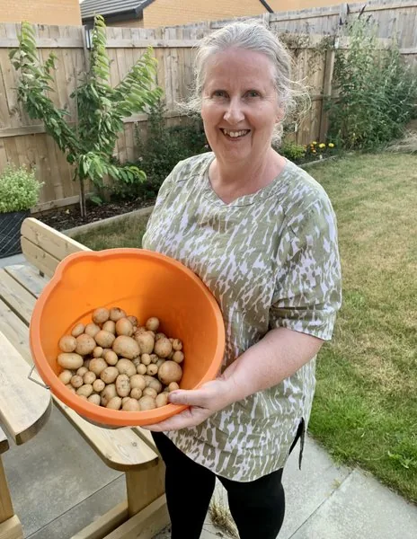 Ethna proudly holding a large bucket of home-grown potatoes