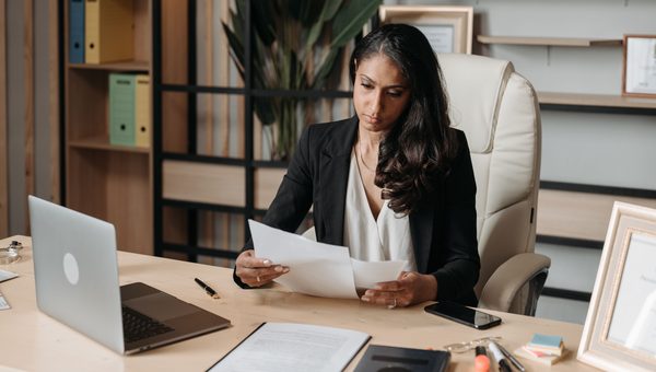 Professional woman alone at her desk reviewing compliance documents